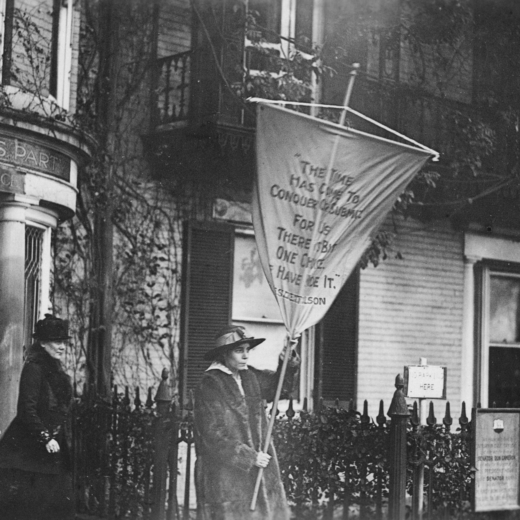 Alice Paul holds a flag and leads a protest