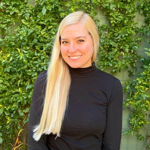 Elizabeth Vogt standing in front of a greenery wall, smiling.