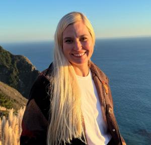 Elizabeth Vogt standing near cliff and body of water, smiling.